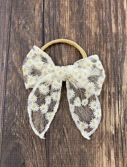 White lace bow hair tie with daisy print detail-approximately 4x5 inches.