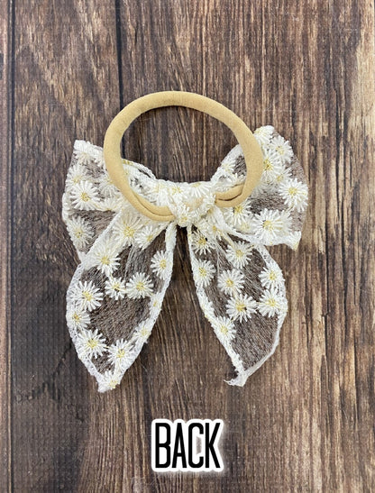 White lace bow hair tie with daisy print detail-approximately 4x5 inches.