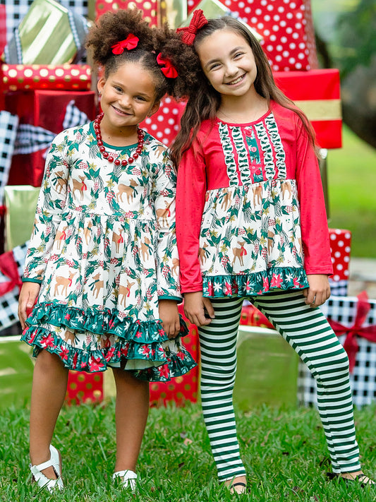 Two young girls dressed in matching Reindeer Games outfits in front of a large pile of presents.