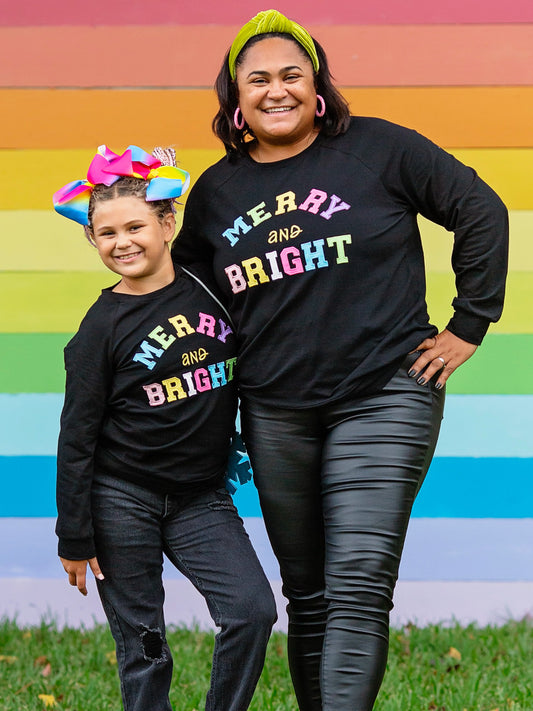 Mommy & Me Black long sleeve top with Merry & Bright in colorful font on a mom and her daughter.