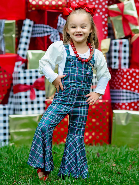 Green plaid jumper on a little girl standing in front of Christmas presents.