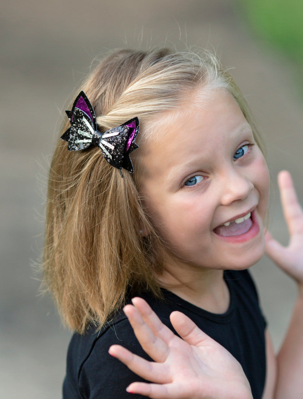 Black and hot pink glitter cat bow with silver whisker detail- approximately 4 inches across.