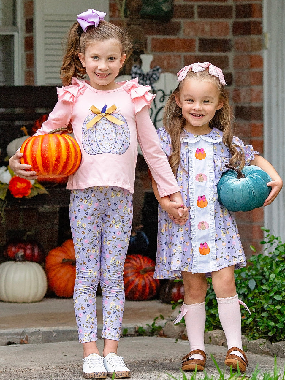 Two young girls in pastel pink and purple themed fall boutique outfits.