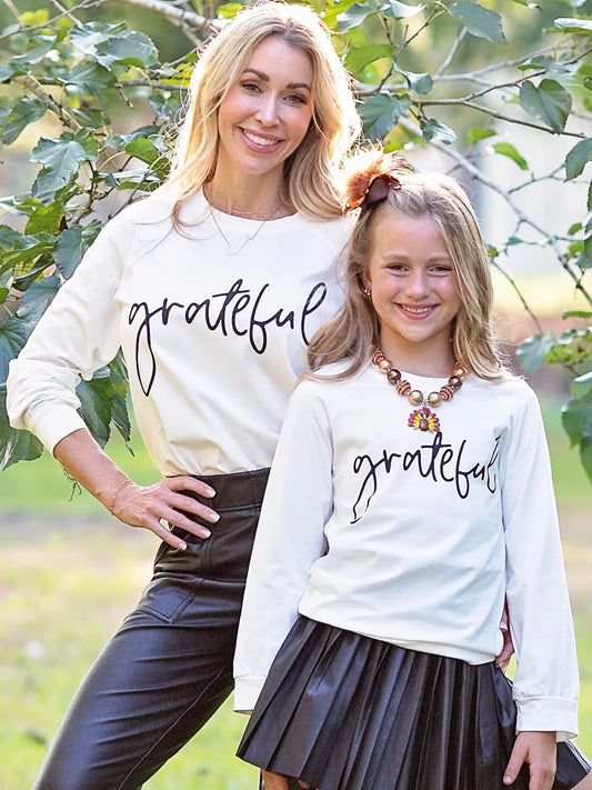 Mom & Me Grateful shirts on a mom and daughter standing outside under a tree.