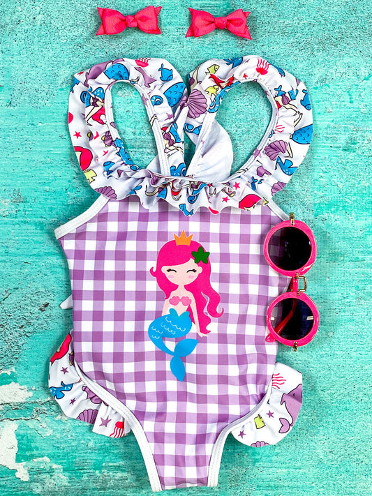 Sweet mermaid with pink hair and gold crown, purple, blue, and red sea animal pattern ruffle, and purple gingham one-piece swimsuit.