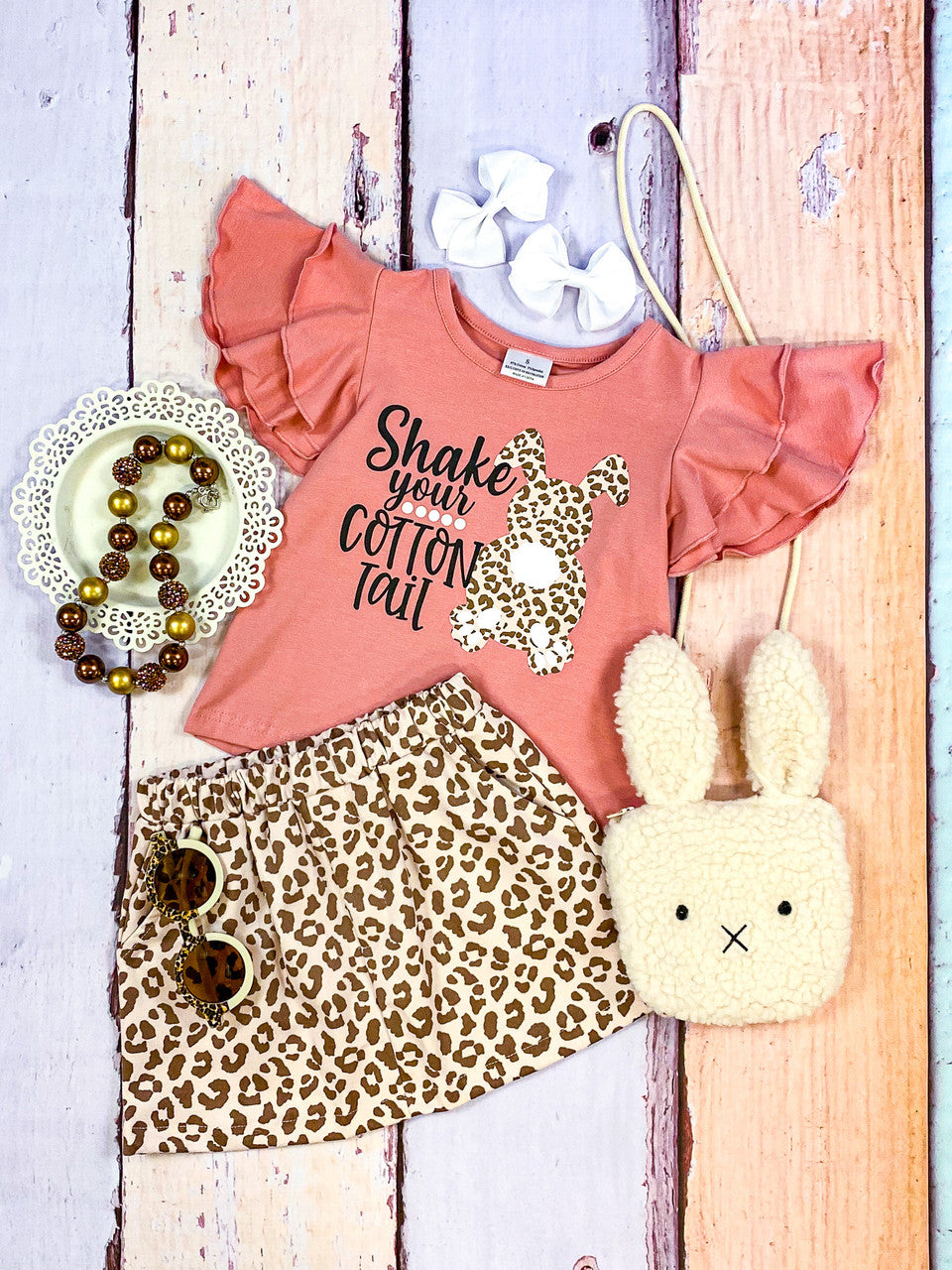 Shake Your Cotton Tail Black lettering with animal print easter bunny, pink top with layered ruffled sleeves paired with animal print skirt.