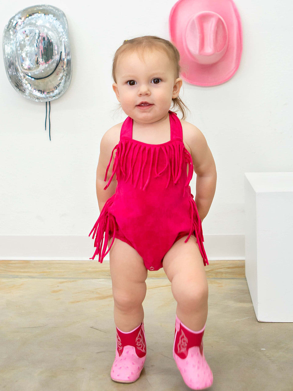 hot pink fringe and halter tie baby romper on model