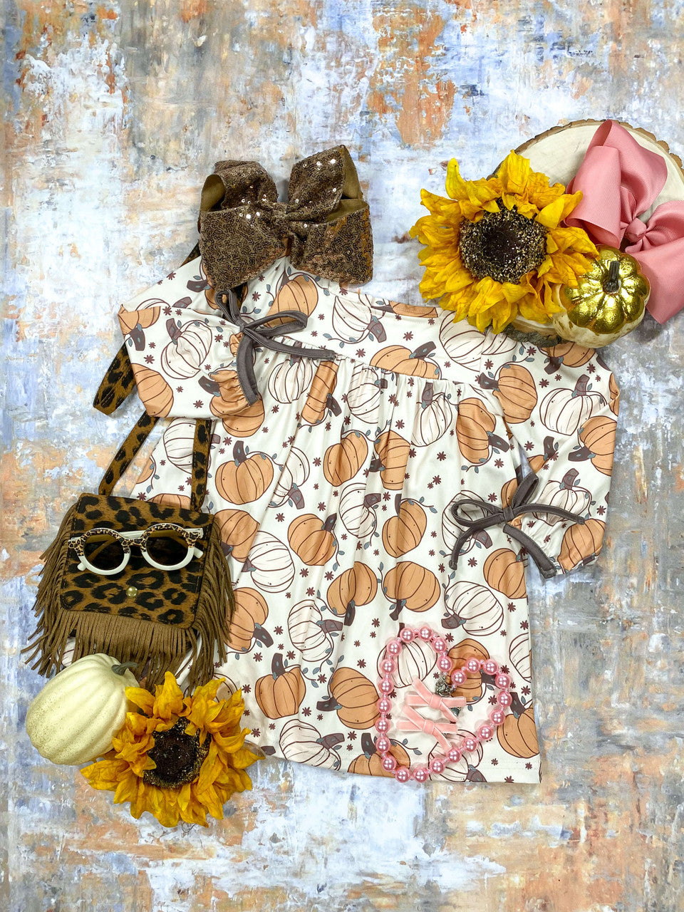 Pumpkin print dress with brown trim and bows on sleeves.