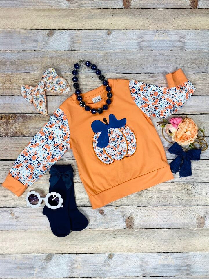 orange shirt with floral sleeves and pumpkin with bow 