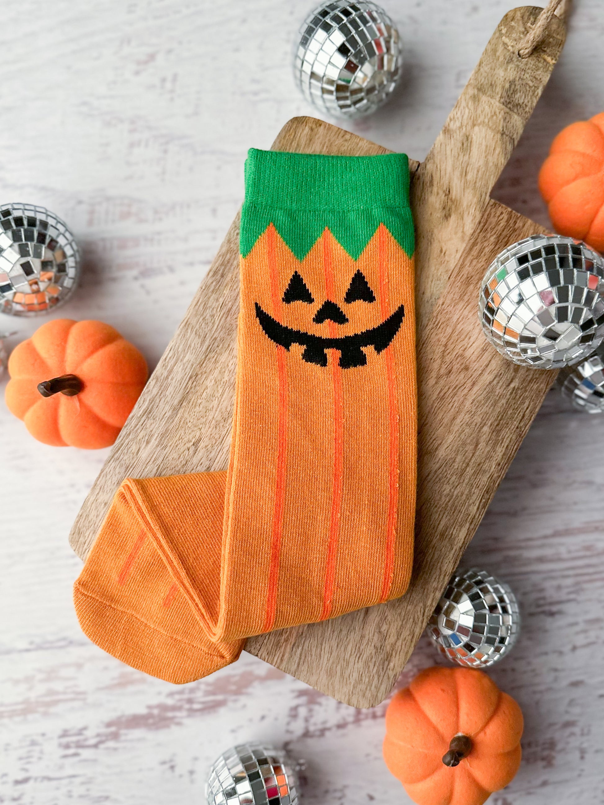 Orange tube socks with green top and black jack-o-lantern face.