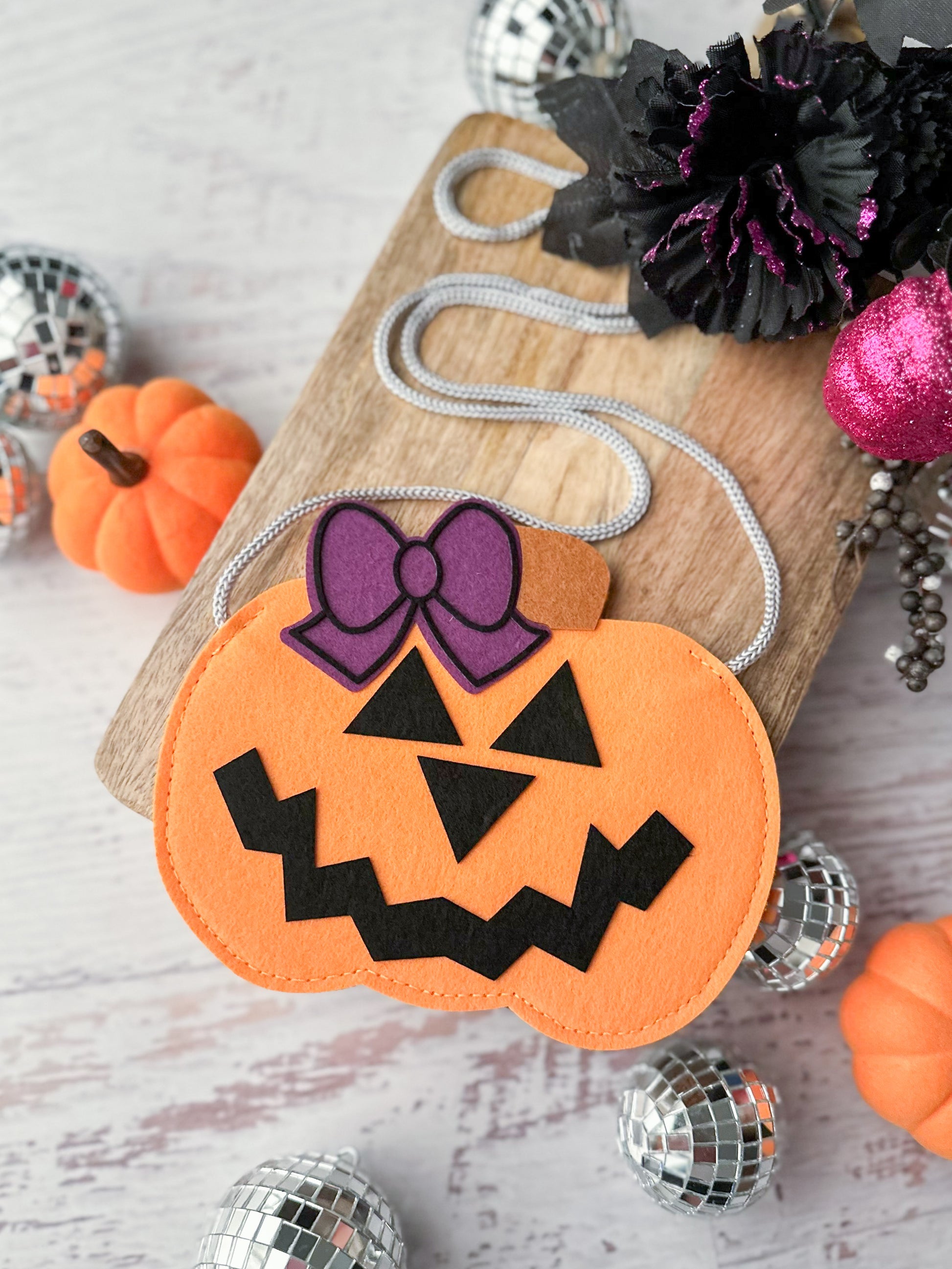 Girl's jack-o-lantern shaped purse in orange with a black face and purple bow