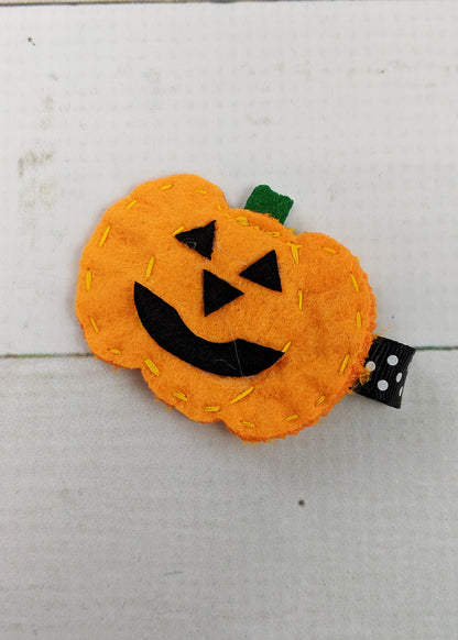 Cute felt orange Jack-o-Lantern pumpkin clippies with stitch details around the edges and green stem. Whether she's sporting her newest Halloween outfit, or you're looking for a fun embellishment for Halloween party goodie bags, you can't go wrong with this adorable hair clip! Get two to wear on pigtails! Each clip is about 2.5-3" long and is affixed to an alligator clip lined with orange with white polka dot ribbon.