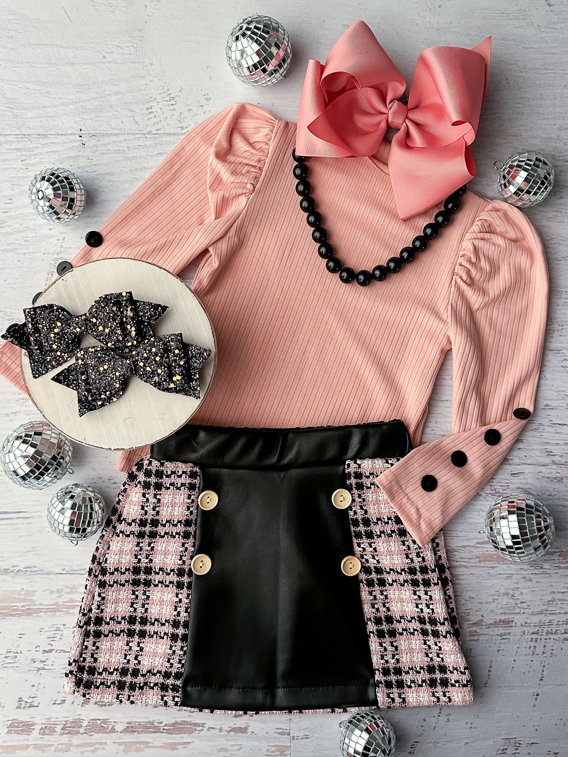 Long sleeve pink ribbed top with button detailing on sleeves with a coordinating plaid and leather skirt