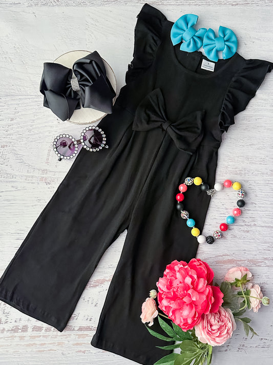 Black jumpsuit with ruffle sleeve details and attached bow in center 