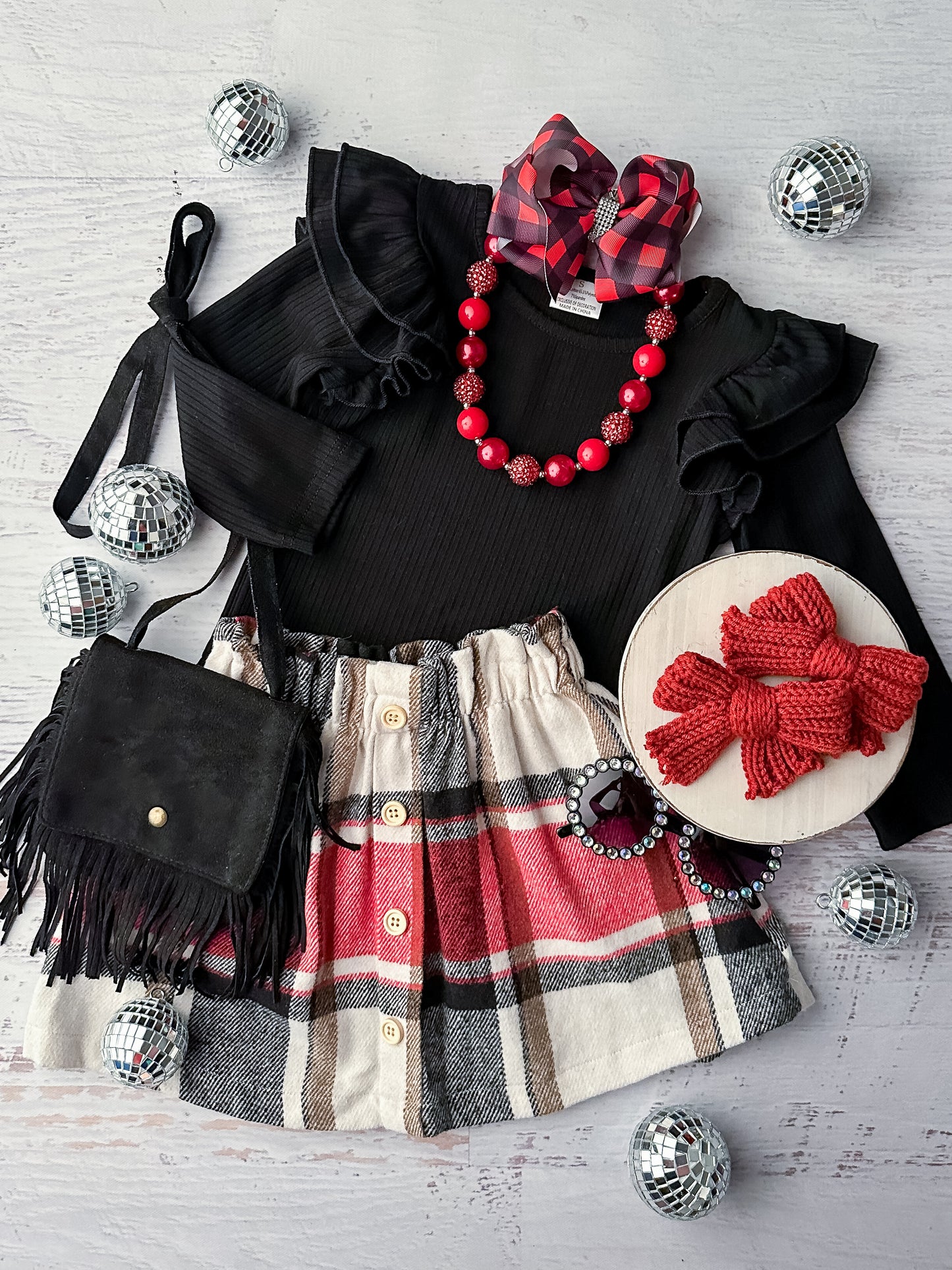 Long sleeve ribbed black top with shoulder ruffles and a plaid flannel skirt with button detailing