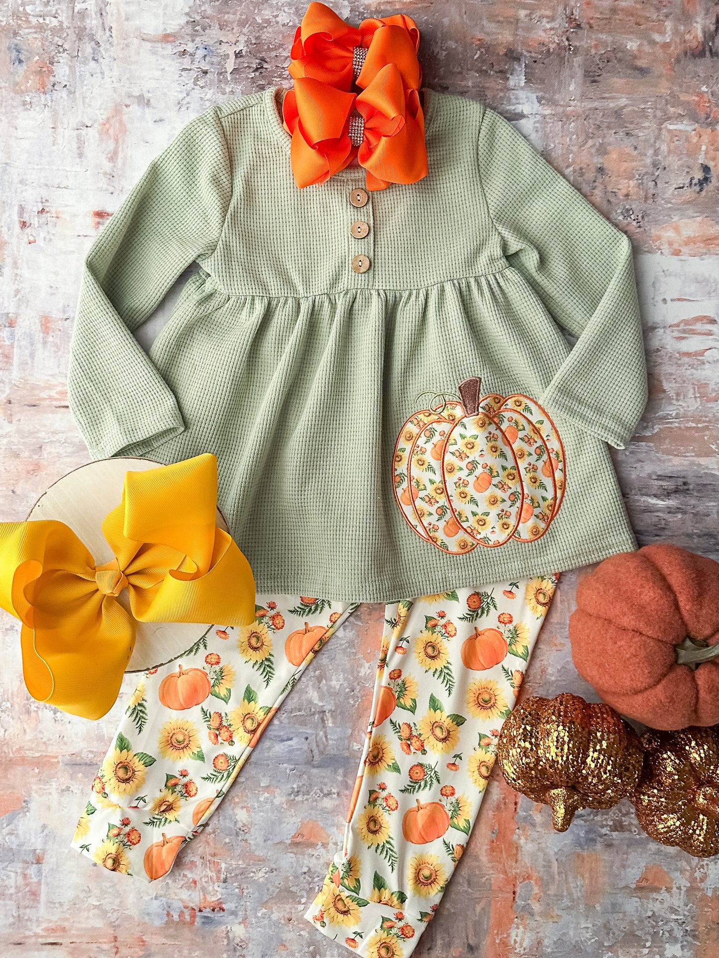 Long sleeve sage green top with button detailing and an appliqué pumpkin and coordinating leggings in a pumpkin print