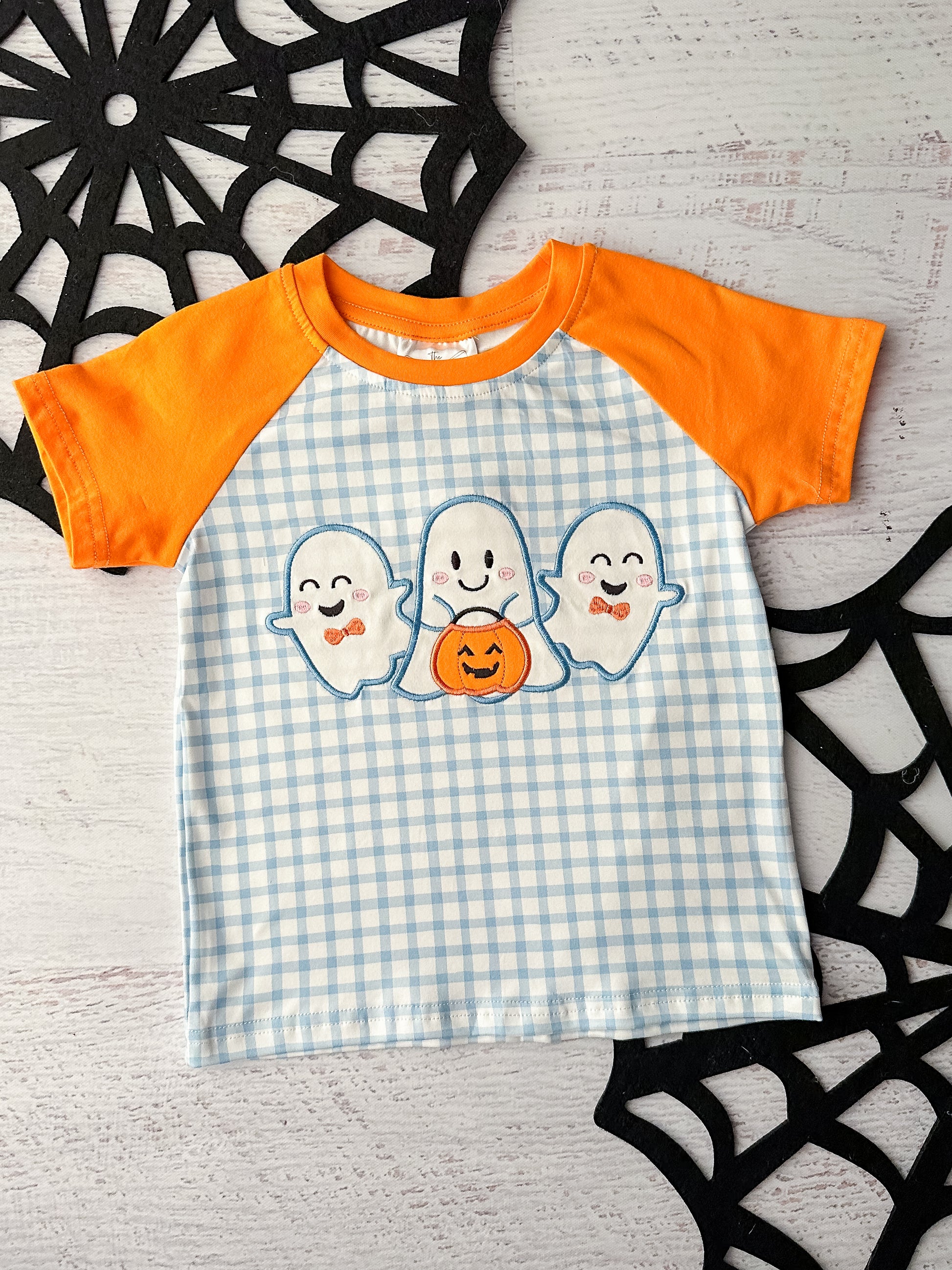 Blue gingham shirt with orange short sleeves and a ghost trio appliqué.