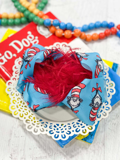 A large double looped grosgrain ribbon hair bow in turquoise cat in the hat print with a red ostrich feather puff the center.  Attaches with a large 3" alligator clip with "teeth" for a secure hold.  The bow measures approximately 6.5" long and 5" wide.