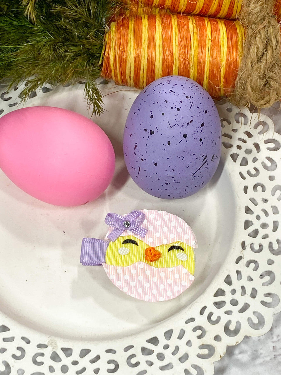 An adorable chick peeking out from a hatched pink polka dot Easter Egg with a lavender bow.