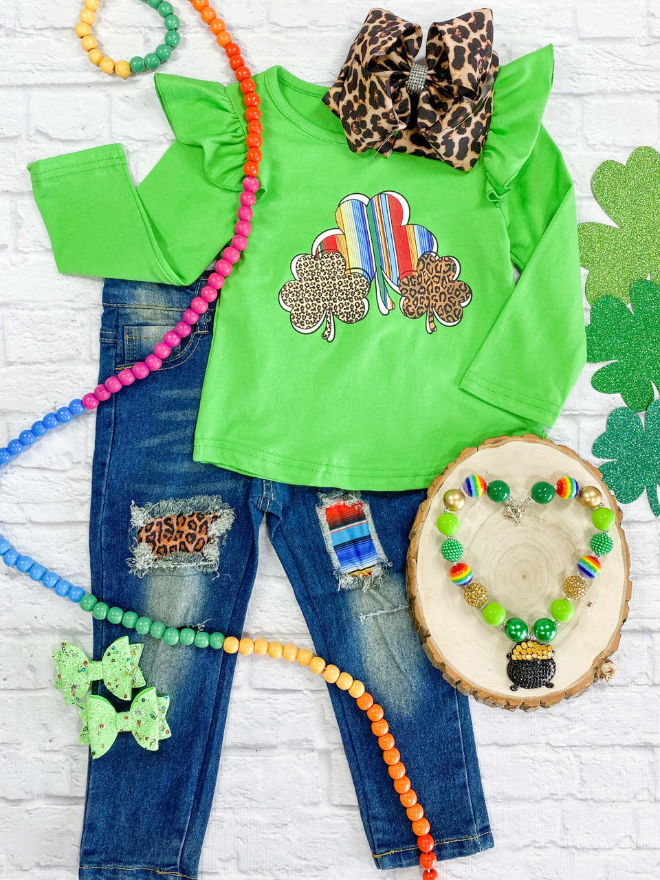 Green top with serape and animal print shamrocks, paired with cutout jeans.