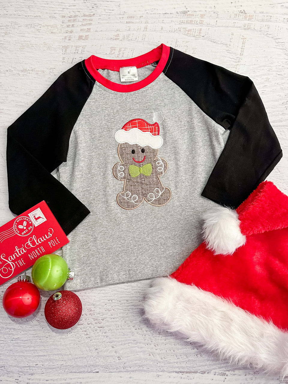 Santa clause hatted gingerbread man with a lime green bow tie, and black baseball sleeve tee. 