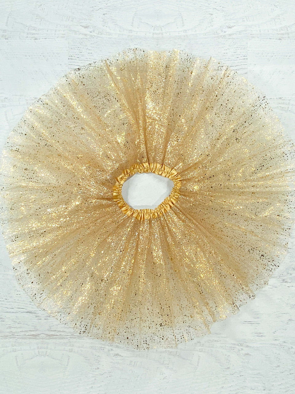 Gold tulle tutu with a metallic gold "splatter." The waist is a stretchy satin lined material to fit a wide age range and the tulle skirt is about 11."  Available in one size only, this tutu fits most kids between 2-8 years.