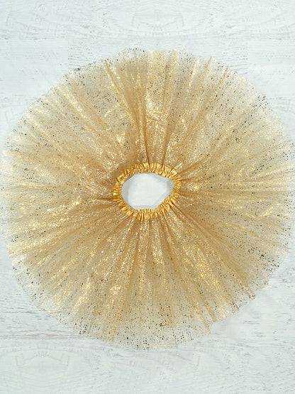 Gold tulle tutu with a metallic gold "splatter." The waist is a stretchy satin lined material to fit a wide age range and the tulle skirt is about 11."  Available in one size only, this tutu fits most kids between 2-8 years.