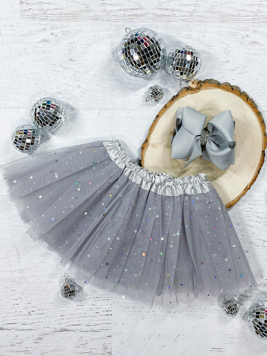 This soft grey tutu is made from polyester tulle, with a silver satin elastic waistband.  The top of three layers is covered with silver sparkle dots in varying sizes.  