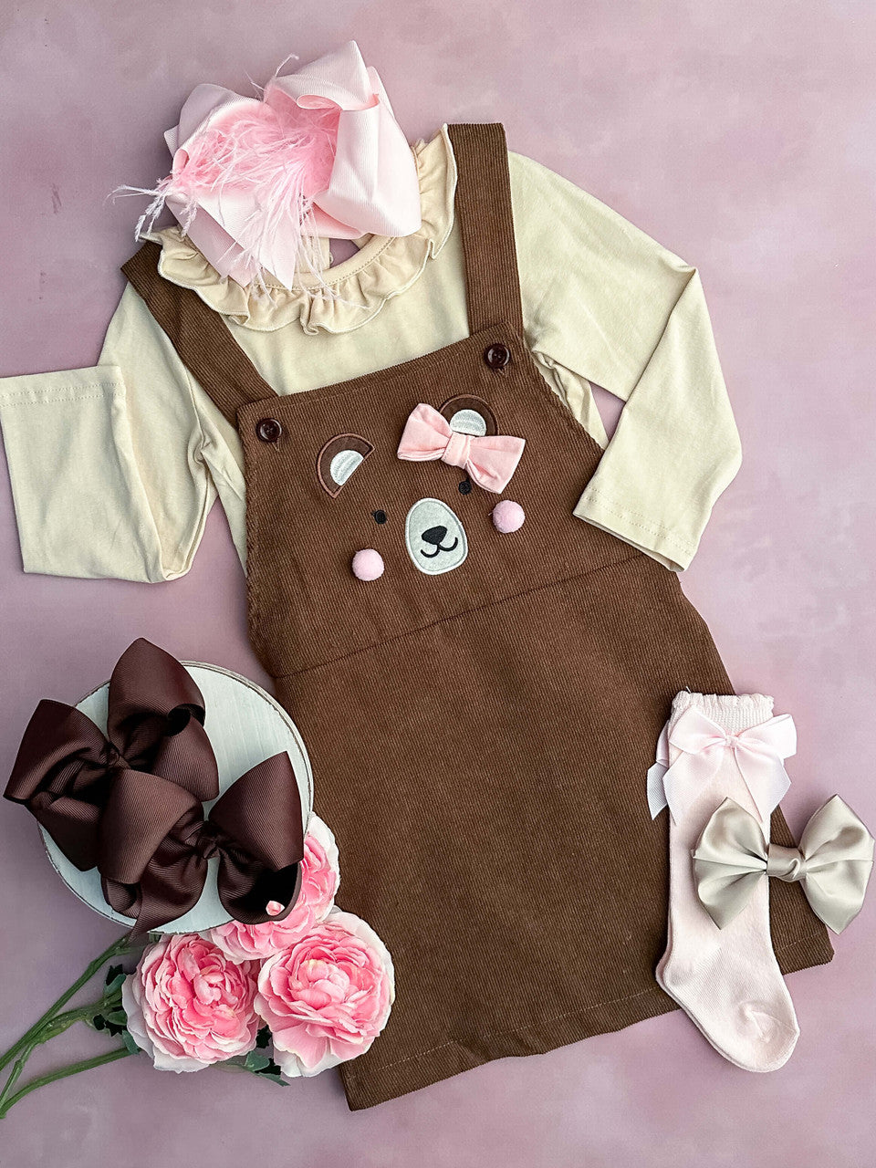 Brown jumper dress with teddy bear face design and tan long sleeve undershirt.