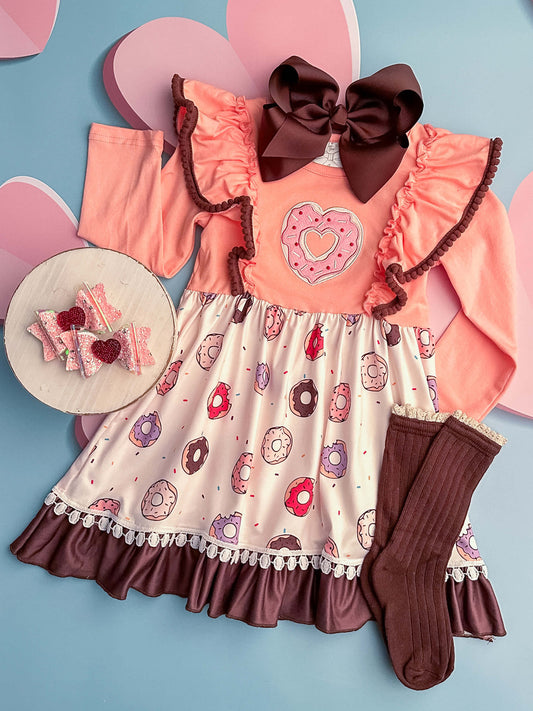 Pink long sleeve ruffle dress with brown trim details, donut fabric and a donut applique design.