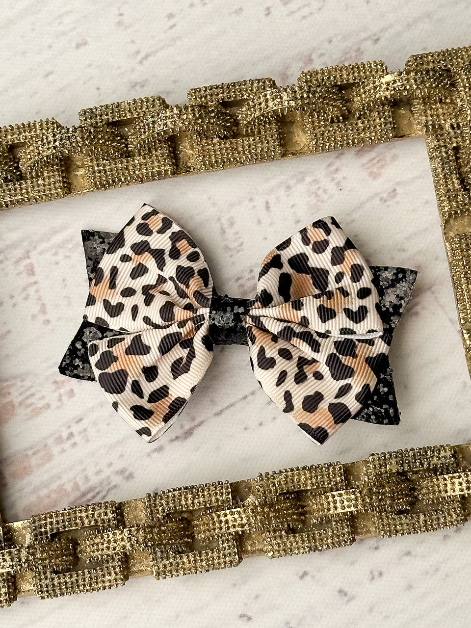 Animal print and black glitter bow on a single alligator clip- approximately 4 inches across.