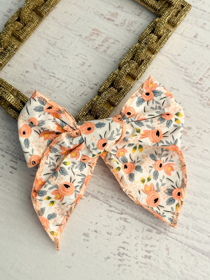 Coral floral print bow with removable single alligator clip. Measures approximately 5x5 inches.