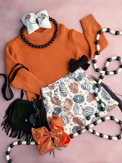 Orange sweater with a pumpkin print fringe skirt in white, orange and black.