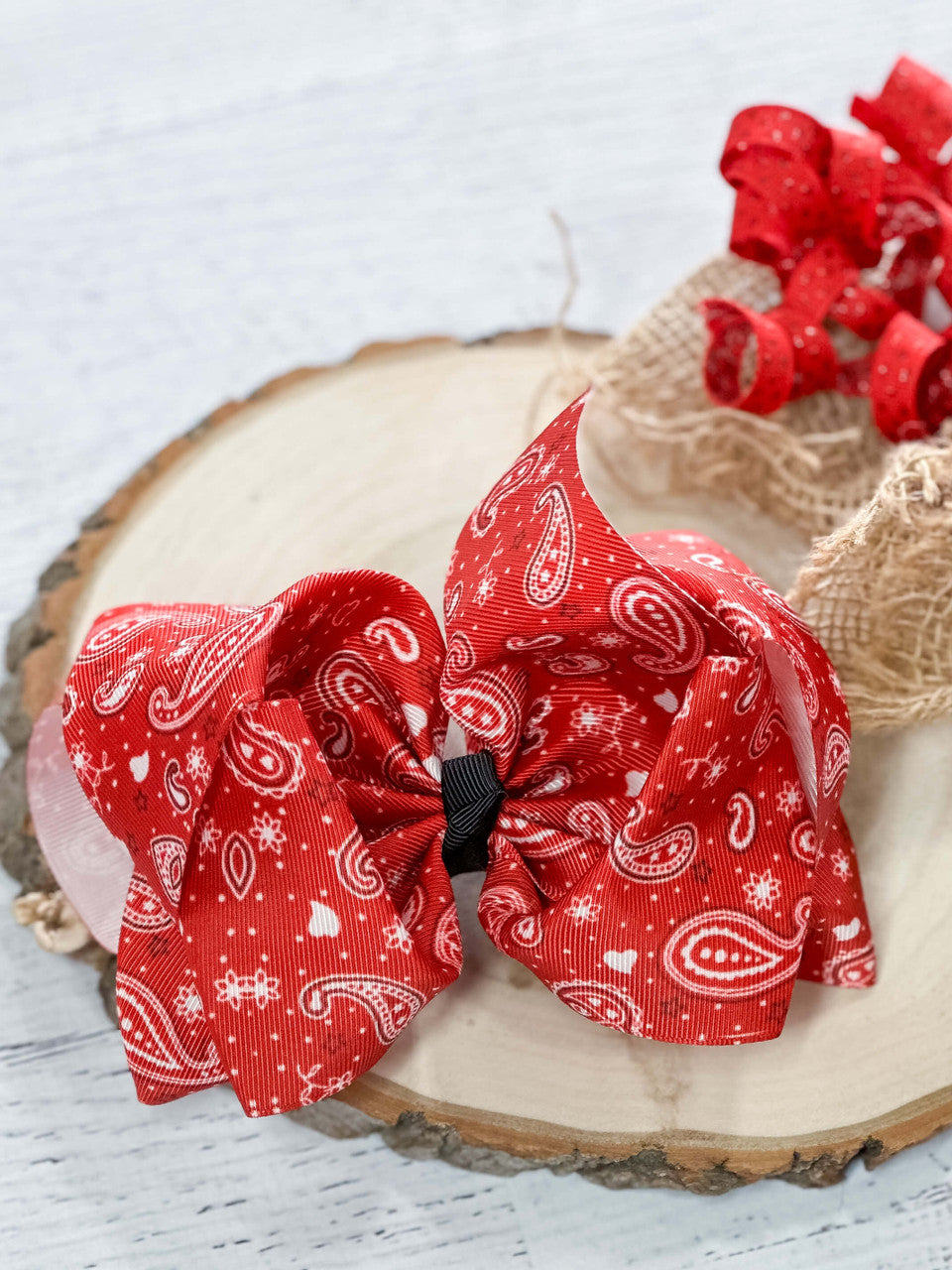 A large double looped grosgrain ribbon hair bow in a fun red bandana print.  Attaches with a large 3" alligator clip with "teeth" for a secure hold.  The bow measures approximately 6.5" long and 5" wide.