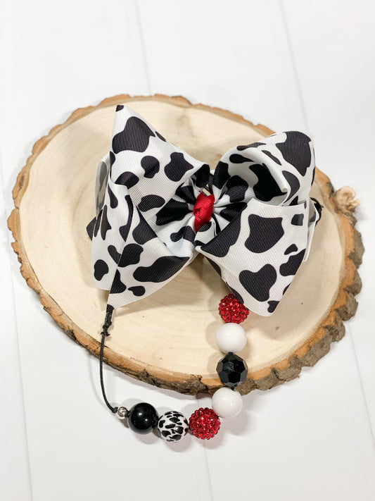 A large double looped grosgrain ribbon hair bow in a cute black and white cow print.