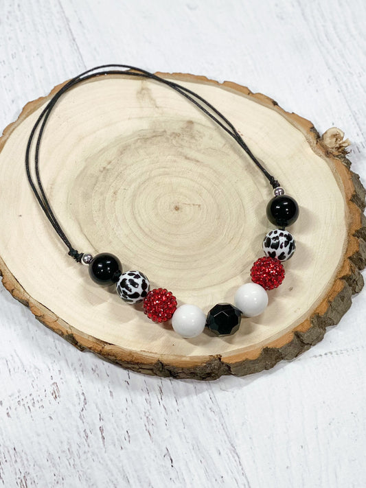 Adjustable wax-coated rope chunky bead necklace with cow print, red rhinestone, solid black, and solid white chunky beads.