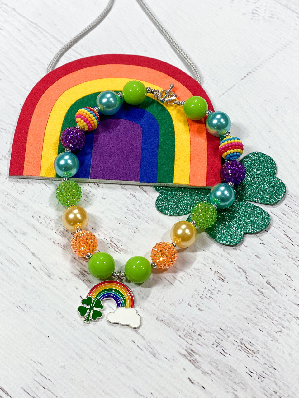 Four-leaf clover, rainbow with cloud pendant chunky bead necklace with sparkly lime green, purple, orange, and solid blue, lime green beads, and a heart toggle closure.