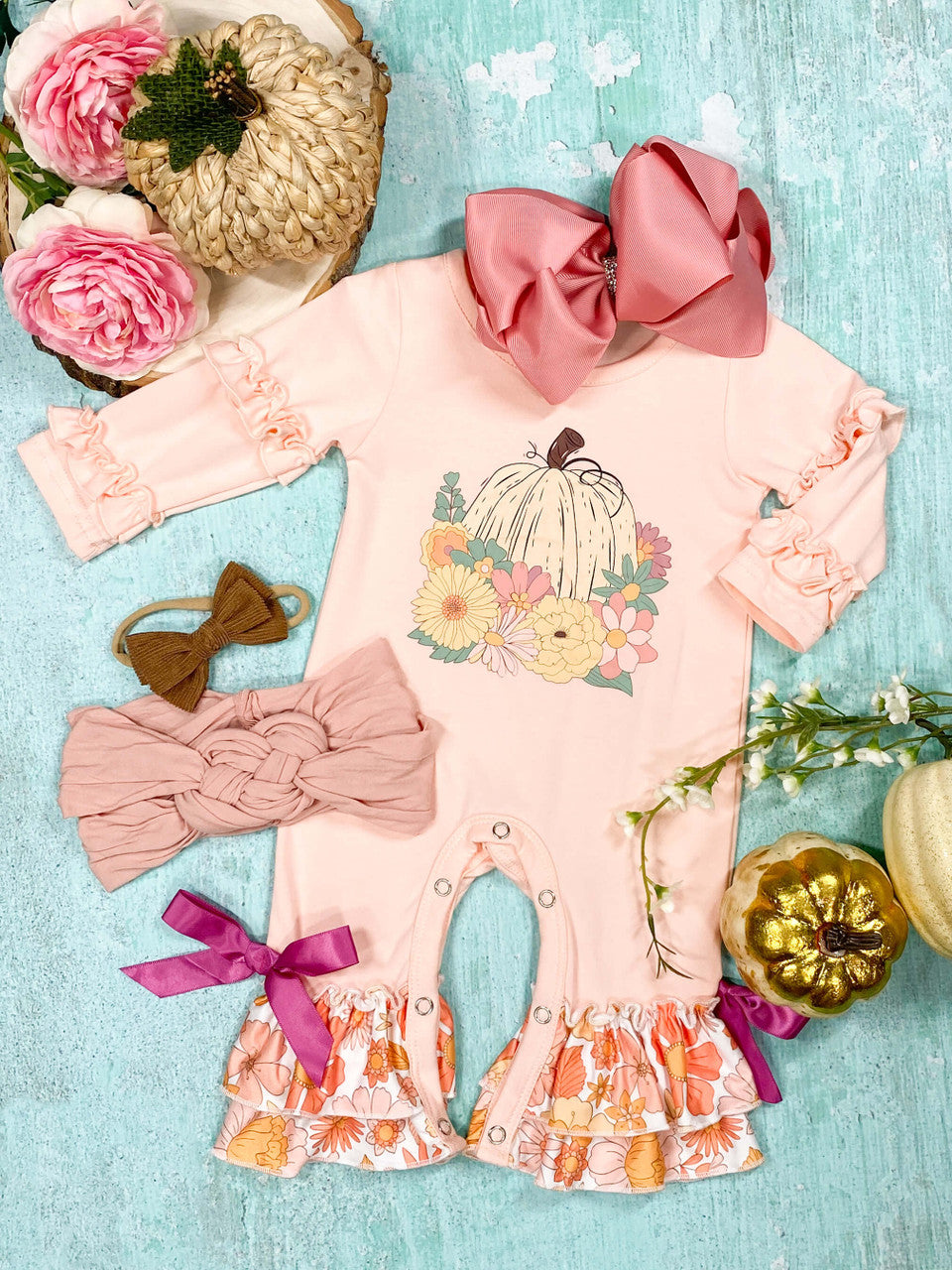 pastel pink baby romper with ruffles, pumpkins, and flowers