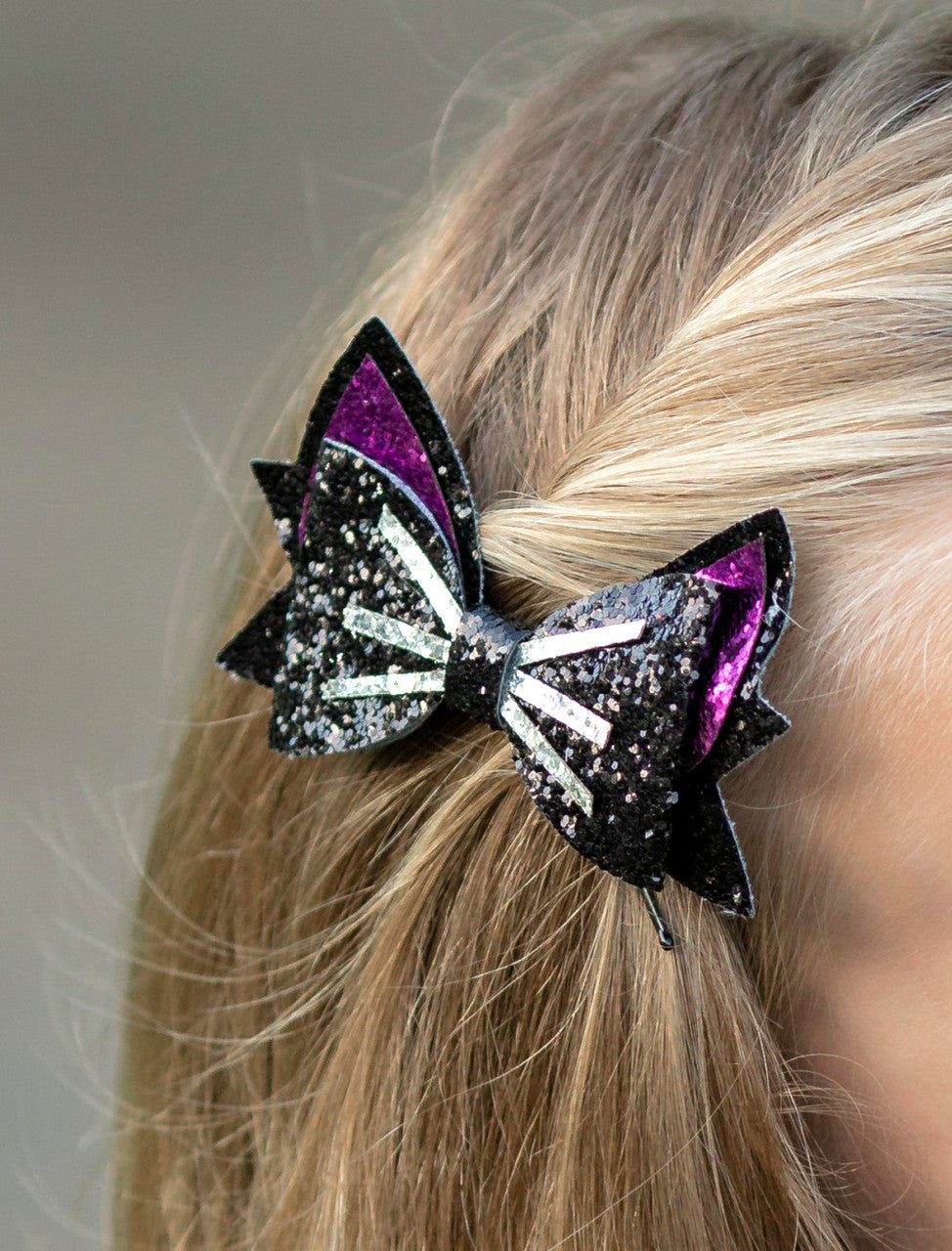 Black and hot pink glitter cat bow with silver whisker detail- approximately 4 inches across.