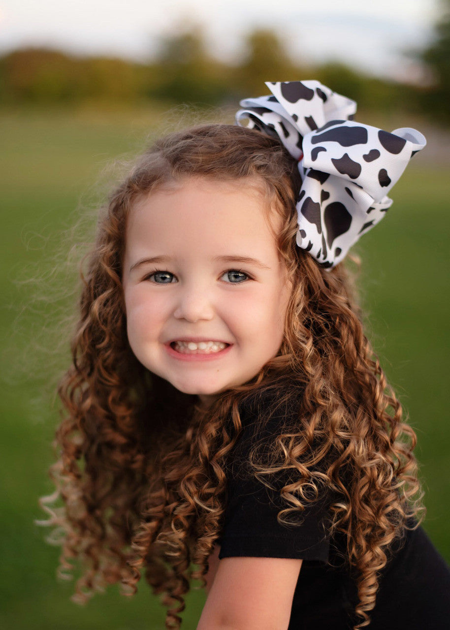 A large double looped grosgrain ribbon hair bow in a cute black and white cow print.  Attaches with a large 3" alligator clip with "teeth" for a secure hold.  The bow measures approximately 6.5" long and 5" wide.