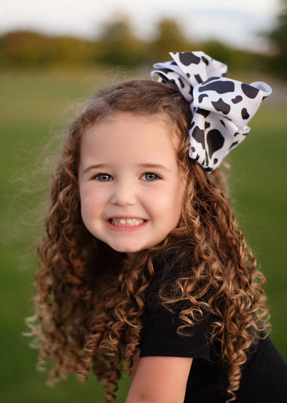 A large double looped grosgrain ribbon hair bow in a cute black and white cow print.  Attaches with a large 3" alligator clip with "teeth" for a secure hold.  The bow measures approximately 6.5" long and 5" wide.