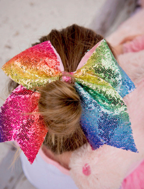 Model wearing Rainbow sequin cheer bow for girls.