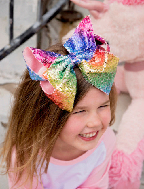 Rainbow sequin extra large Texas size hair bow for girls on model.